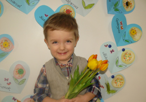 Chłopiec stoi z bukietem kwiatów dla Babci i Dziadka